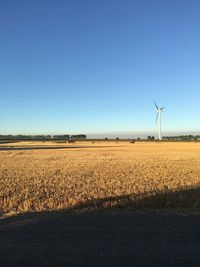 Wind turbines on field against clear sky