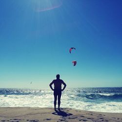 Full length of man standing on beach against clear blue sky