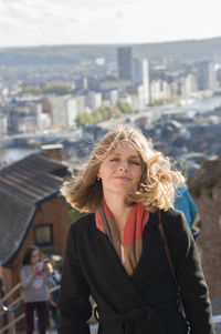 Portrait of a beautiful young blonde girl with flying hair in the sun, the city