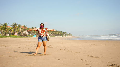 Full length of young woman at beach against sky