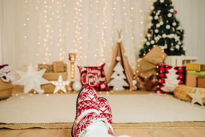 Woman feet wearing christmas shoes indoor over christmas decoration