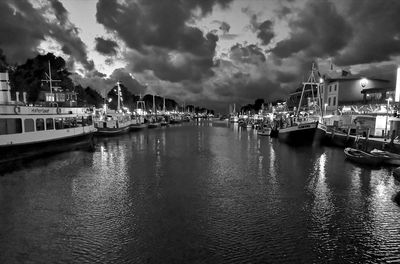 View of harbor in city against cloudy sky