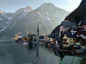 Buildings in town by lake against mountains