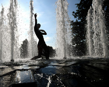 Silhouette man splashing water in fountain