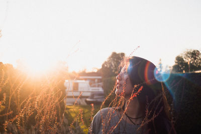 Beautiful woman looking away while standing against sky during sunset