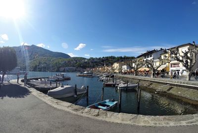 Boats moored at harbor against sky in city