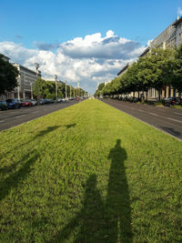 Shadow of man on grass at karl-marx-allee, berlin