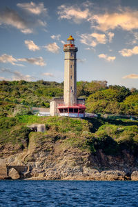 Lighthouse by sea against sky