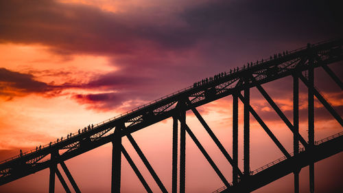 Low angle view of silhouette suspension bridge against cloudy sky
