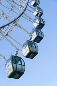 Closeup of colorful cabins of giant ferris wheel in amusement park against blue sky