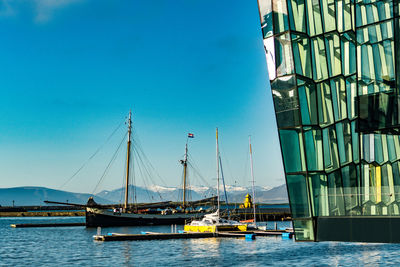 Sailboats moored on sea against blue sky