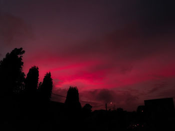 Low angle view of silhouette trees against dramatic sky