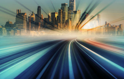 Light trails on illuminated buildings in city against sky