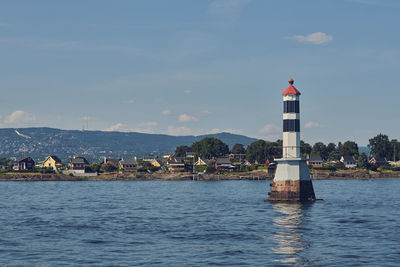 Lighthouse amidst sea against sky