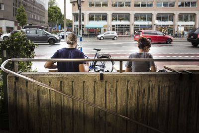 Rear view of man and woman sitting at sidewalk cafe in city