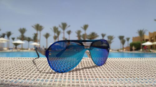 Close-up of sunglasses on swimming pool against sky