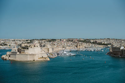 Panoramic view of sea and buildings against clear blue sky