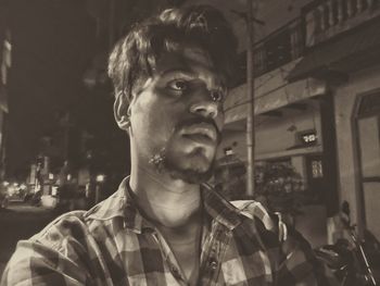 Portrait of young man looking away in city at night