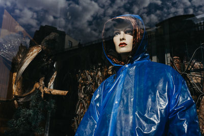 Portrait of young woman standing by sculpture against trees