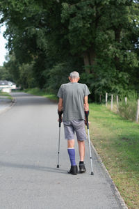 A man with a broken leg is walking down the street, on his left leg he has special boot for walking