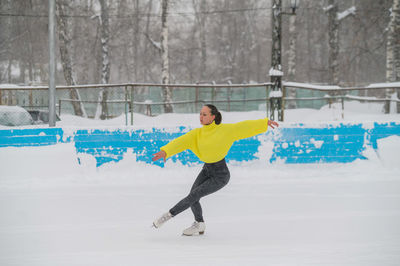 Full length of woman skating on snow covered field