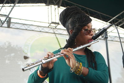 Young woman playing flute in front of microphone