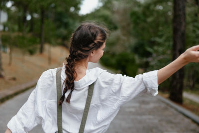 Young woman standing against trees