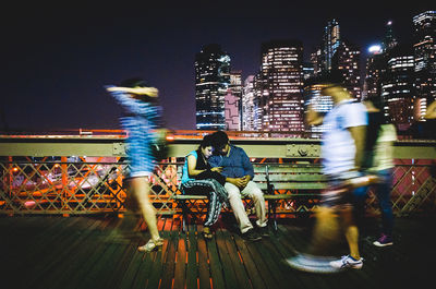 People on illuminated buildings in city at night