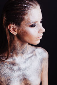 Close-up portrait of young woman against black background