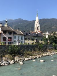 View of bressanone brixen with river, buildings and mountains against sky