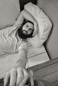 Portrait of young man lying on bed at home