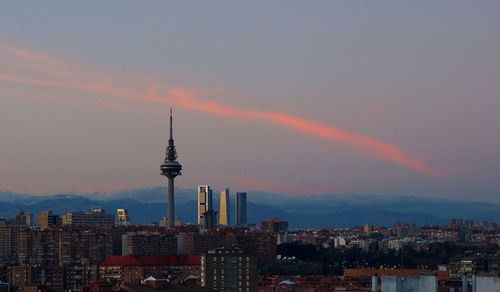 Illuminated buildings in city against sky during sunset