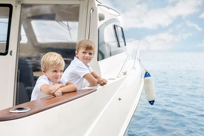 Brothers looking at sea while standing on yacht