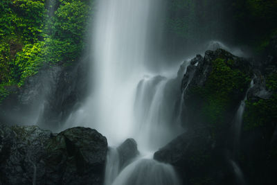 Beauty waterfall in motion of rock and blue leaves
