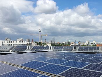 High angle view of solar panels in city against cloudy sky