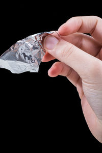 Close-up of hand holding foil over black background