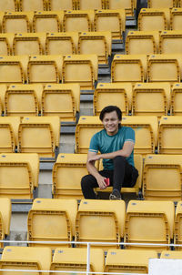 Smiling young man sitting on chair in stadium