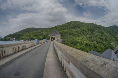 Road passing through mountain against cloudy sky