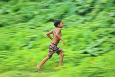 Full length of shirtless boy running in field