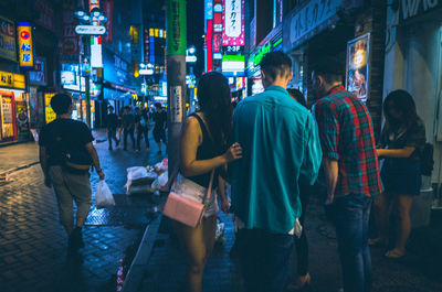 People walking on illuminated street at night