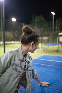 Woman by table tennis table at night