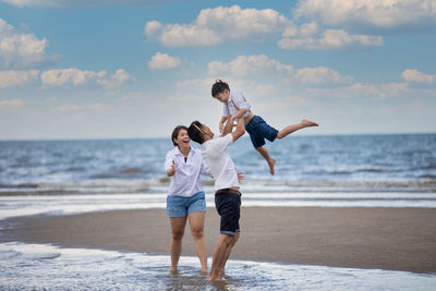 Full length of boys on beach against sky