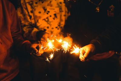 Midsection of people holding sparkler at night