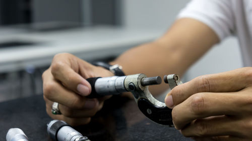 Cropped hands holding equipment at desk