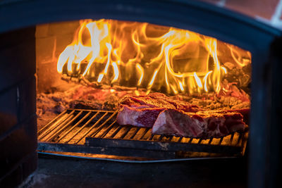 A traditional oven with a burning fire inside for cooking. inside, raw meat is cooked on 