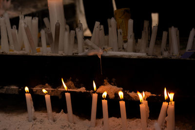 Candles lit in a dark place for prayer. religious request concept. yellow candlelight