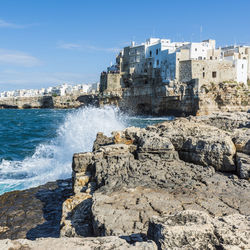 Rocks on beach against buildings in city