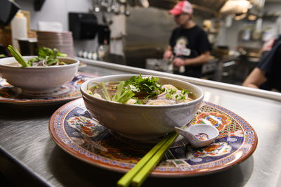 Two bowls of pho soup ready to go out to customers from the kitchen