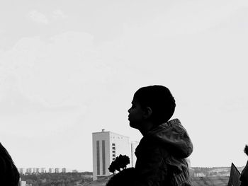 Side view of boy looking against sky