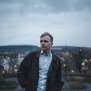 Young man looking away against sky